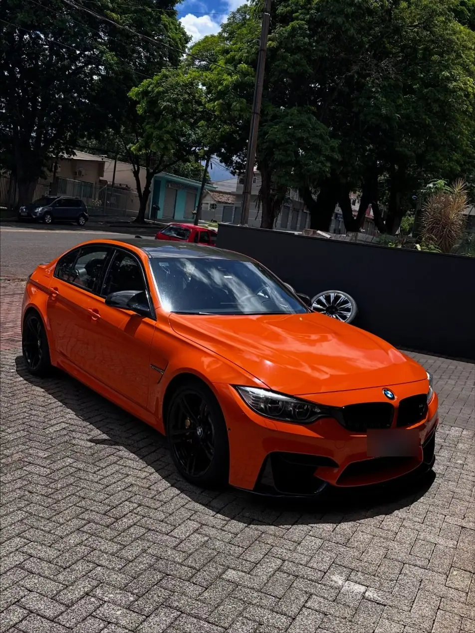 BMW M3 laranja em três quartos com rodas pretas