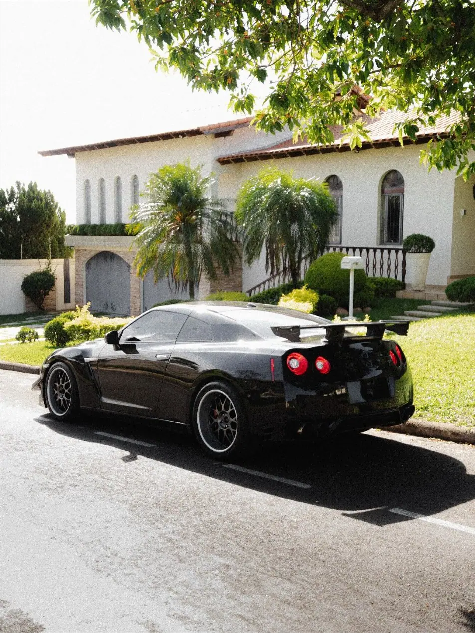 Nissan GT-R R35 preto visto de trás em uma rua arborizada